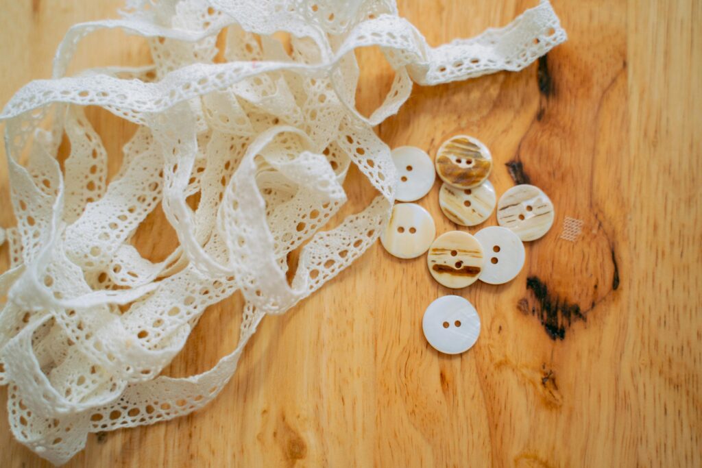 A close-up view of elegant lace ribbon paired with buttons on a wooden table.